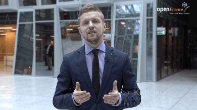 Mężczyzna w garniturze i krawacie stojący przed budynkiem.