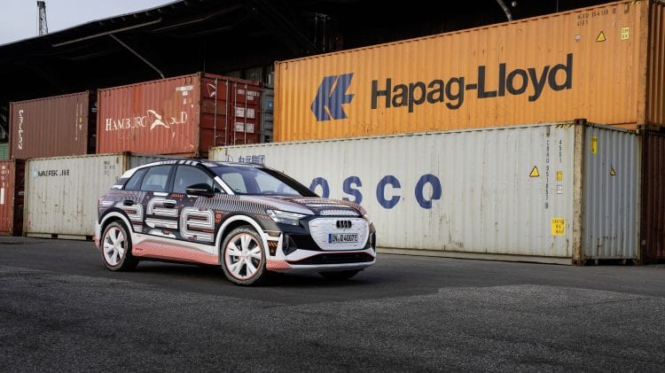 Audi Q4 e-tron stoi zaparkowane przed kontenerami transportowymi.