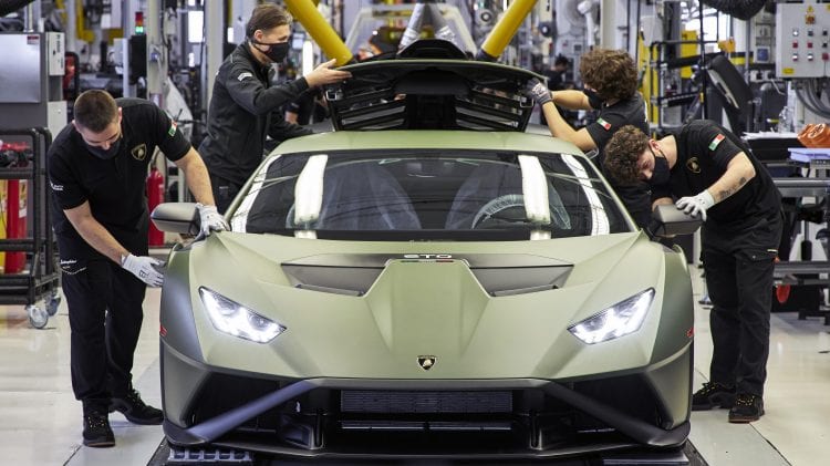 Grupa mężczyzn pracuje nad sportowym samochodem Lamborghini, który będzie wystawiony na sprzedaż w pierwszym kwartale.