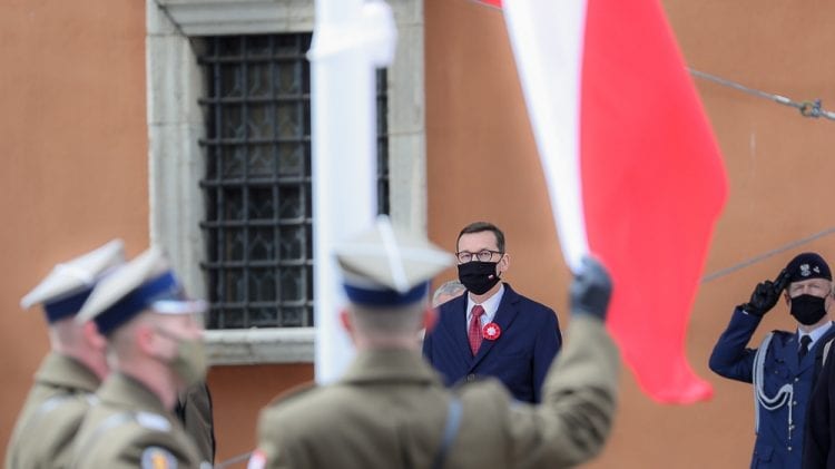Mężczyzna w mundurze wojskowym macha flagą przed grupą osób podczas podpisywania wspólnej deklaracji z Prezydentami Polski, Litwy i Estonii.