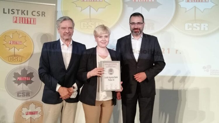 Trzy osoby stojące przed ekranem z nagrodą Banku Credit Agricole za Srebrny Listek CSR POLITYKI.