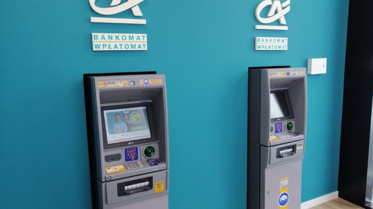 Dwa bankomaty Credit Agricole przed niebieską ścianą.