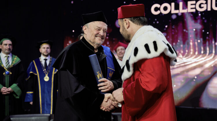 Dwóch mężczyzn, profesor honorowy i Znany wokalista, ściskają dłonie podczas uroczystości wręczenia dyplomów w Collegium Humanum.
