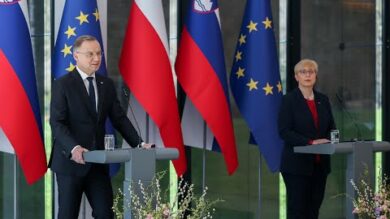 Dwóch urzędników przemawiających na podium z flagami Słowenii i Unii Europejskiej w tle.