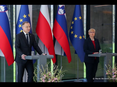 Dwóch urzędników przemawiających na podium z flagami Słowenii i Unii Europejskiej w tle.