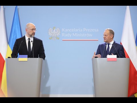 Dwóch urzędników stojących na podium z flagami Ukrainy i Polski, biorących udział w konferencji prasowej.