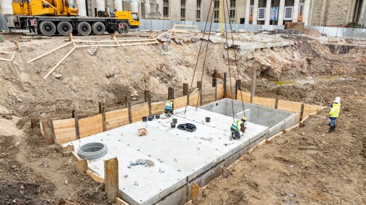 Pracownicy budowlani na wczesnym etapie budowy z betonowym fundamentem.