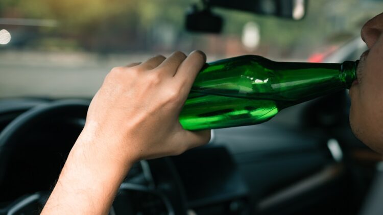 Osoba pijąca z butelki podczas jazdy.