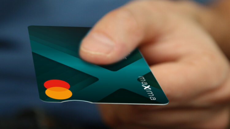 Dłoń trzymająca zamazaną kartę kredytową, z naciskiem na projekt karty przedstawiający częściowo zielone i niebieskie tło oraz czerwono-żółte logo w kształcie koła.