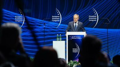 Mężczyzna przemawia na podium, w tle transparenty „Europejskiego Kongresu Gospodarczego”; publiczność na pierwszym planie.